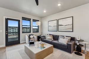 Living room featuring light wood finished floors, baseboards, a ceiling fan, and recessed lighting