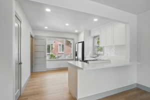 Kitchen with stainless steel fridge with ice dispenser, recessed lighting, white cabinets, light countertops, and decorative backsplash