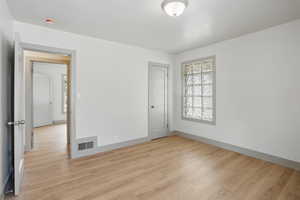 Spare room featuring light wood-style flooring, baseboards, and a smoke detector