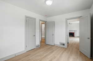 Unfurnished bedroom with light wood-type flooring, a fireplace, and baseboards