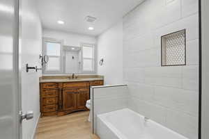 Bathroom with toilet, wood finished floors, a bath, vanity, and a shower