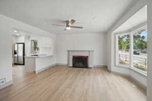 Unfurnished living room with a sink, plenty of natural light, light wood-type flooring, and recessed lighting