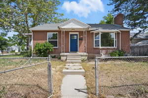 View of front of home featuring a chimney, a gate, a fenced front yard, and brick siding