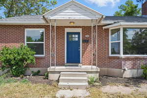 Entrance to property with brick siding and a shingled roof