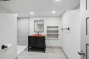 Full bath with tiled shower, recessed lighting, vanity, and wood finished floors