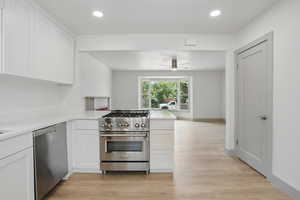 Kitchen featuring appliances with stainless steel finishes, a peninsula, light countertops, white cabinetry, and light wood-type flooring