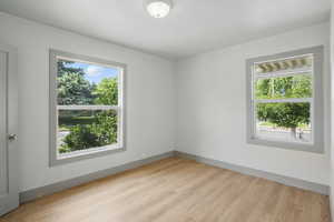 Unfurnished room featuring healthy amount of natural light, light wood-type flooring, and baseboards