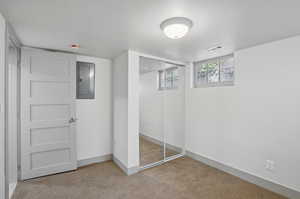 Unfurnished bedroom featuring electric panel, carpet floors, a closet, and baseboards