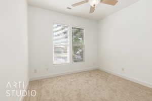 Empty room featuring carpet, visible vents, ceiling fan, and baseboards