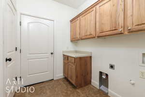 Laundry area with electric dryer hookup, baseboards, and cabinet space