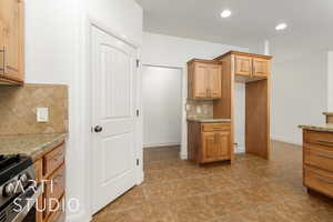 Kitchen featuring tasteful backsplash, stainless steel gas range oven, baseboards, and light stone counters