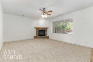 Unfurnished living room with carpet flooring, a ceiling fan, a stone fireplace, visible vents, and baseboards