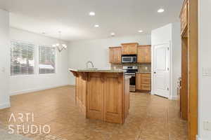 Kitchen with tasteful backsplash, recessed lighting, stainless steel appliances, a notable chandelier, and a kitchen breakfast bar