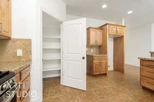 Kitchen featuring recessed lighting, light stone countertops, stainless steel range with gas stovetop, light tile patterned floors, and tasteful backsplash