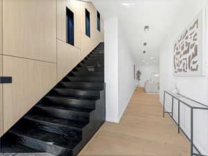 Stairway with wood finished floors and baseboards