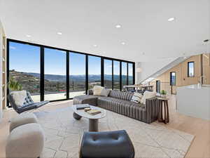 Living room featuring light wood finished floors, a mountain view, floor to ceiling windows, and recessed lighting