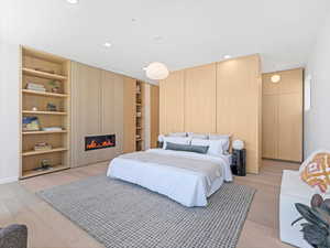Bedroom with light wood-type flooring, a fireplace, and recessed lighting