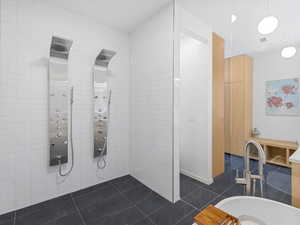 Bathroom featuring tile patterned floors, tile walls, and a tile shower