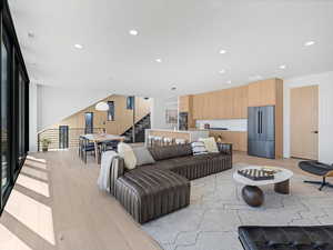 Living room featuring light wood-type flooring, recessed lighting, visible vents, and stairs