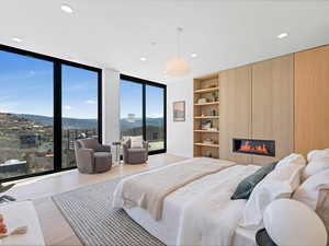 Bedroom with expansive windows, a large fireplace, recessed lighting, access to exterior, and wood finished floors