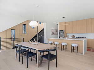 Dining space featuring stairway, light wood-style flooring, and wooden walls
