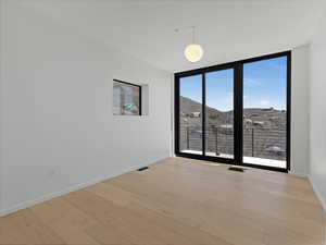 Empty room with visible vents, baseboards, light wood finished floors, and floor to ceiling windows