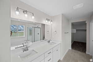 Bathroom featuring a sink, tile patterned flooring, double vanity, and a stall shower