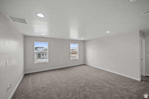 Carpeted spare room with baseboards, visible vents, and recessed lighting