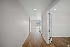 Corridor featuring wood finished floors, baseboards, and recessed lighting