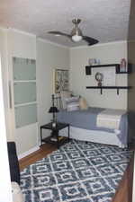 Bedroom featuring crown molding, a textured ceiling, ceiling fan, and wood finished floors