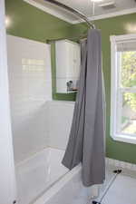 Bathroom with visible vents, baseboards, shower / tub combo with curtain, water heater, and ornamental molding