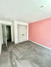 Unfurnished bedroom featuring visible vents, baseboards, carpet floors, and a closet
