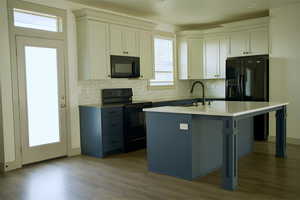 Kitchen with a sink, tasteful backsplash, black appliances, and wood finished floors