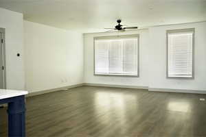 Unfurnished living room featuring baseboards, a ceiling fan, and wood finished floors