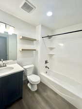 Full bathroom with wood finished floors, shower / bathing tub combination, vanity, toilet, and visible vents