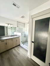 Full bathroom with vanity, wood finished floors, visible vents, and a shower stall