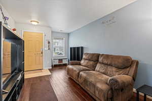 Living room with dark wood-type flooring, a textured ceiling, and baseboards