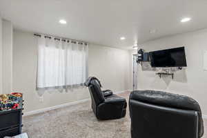 Living area with carpet floors, baseboards, and recessed lighting