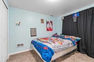 Carpeted bedroom featuring a closet, baseboards, and visible vents