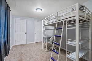 Bedroom with a textured ceiling, carpet flooring, and baseboards