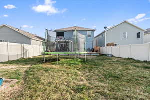 Back of property with a yard, a fenced backyard, and a trampoline