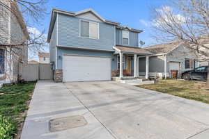 View of front of house with fence, stone siding, a gate, a garage, and driveway