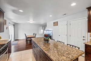 Kitchen featuring dark brown cabinetry, recessed lighting, a kitchen island, dark stone countertops, and stainless steel gas range