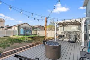Deck featuring a fenced backyard, a trampoline, a residential view, and a pergola