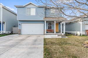 Traditional-style house featuring a front yard, a porch, an attached garage, stone siding, and concrete driveway