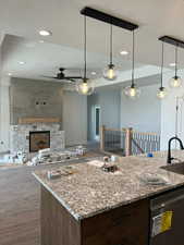 Kitchen featuring a textured ceiling, a sink, open floor plan, dishwasher, and a ceiling fan