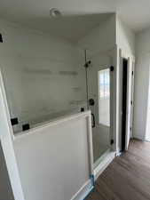 Bathroom with baseboards, wood finished floors, and a stall shower