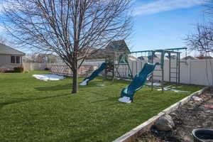 View of jungle gym with a fenced backyard and a lawn