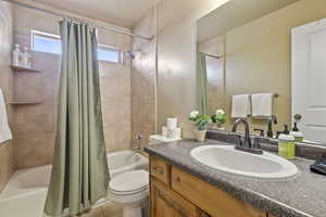 Full bathroom featuring toilet, tile patterned floors, shower / bathtub combination with curtain, and vanity