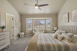 Carpeted bedroom with a textured ceiling, vaulted ceiling, and ceiling fan